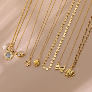 Collection of gold-plated sun and bow necklaces on soft beige silk background