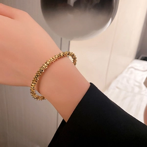 Detailed view of a gold irregular textured metal bracelet on a wrist with unique finish