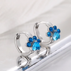 Detalle de pendientes de plata con forma de garra de gato y circonita azul