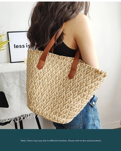Detail view of large straw tote bag featuring brown leather handles and woven texture