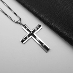 Detail of silver and black punk cross pendant with polished finish on white background