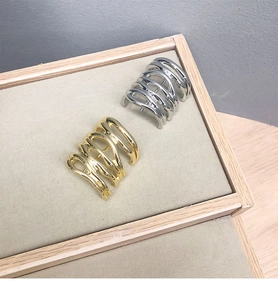 Detail of minimalist gold and silver wavy hair pins on a beige display tray