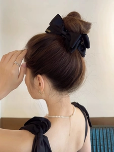 Detail of large black satin bow hair claw clip styled on a classic bun hairstyle