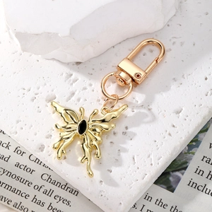 Detail of a gold butterfly keychain with black crystal inlay on white stone and newspaper