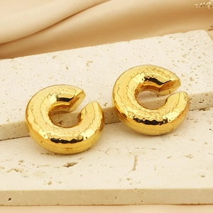 Detail of 18k gold plated C-shaped ear clips with unique hammered metal texture and finish