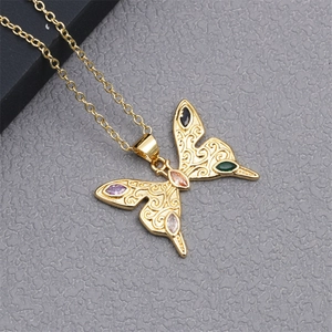 Macro view of gold butterfly pendant with colorful gemstones and hollow pattern