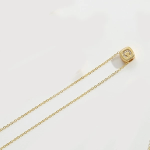 Close-up of golden necklace featuring a cubic pendant with crystal-studded letter C detail
