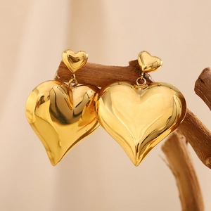 Polished 18K gold plated hollow double heart stud earrings hanging on a wooden branch