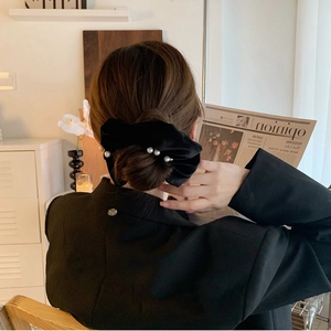 Elegant black velvet hair scrunchie with pearls worn on a sophisticated updo hairstyle