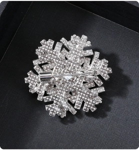 Macro detail showing the silver snowflake brooch back structure and secure safety pin fastener