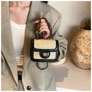Detail of woven straw bag with black PU leather flap and gold flower metallic clasp