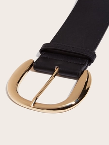 Macro shot of wide black leather belt with oversized gold U-shaped metal buckle