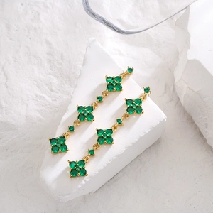 Elegant 18K gold plated clover dangle earrings with green zircon stones on stone background