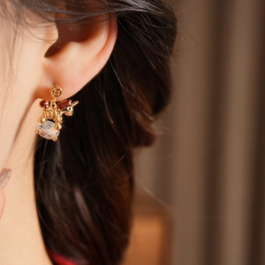 Close-up of golden unicorn earrings with red enamel and sparkling zircon on model