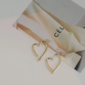 Detailed macro view of heart-shaped gold earrings with polished metallic mirror finish