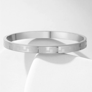 Detailed close-up of a silver stainless steel bracelet featuring geometric Greek key patterns