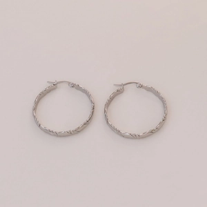 Dettaglio di orecchini a cerchio intrecciati argentati con design a spirale e chiusura sicura