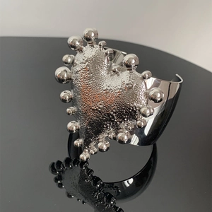 Macro view of wide silver heart cuff with hammered texture and metallic bead accents