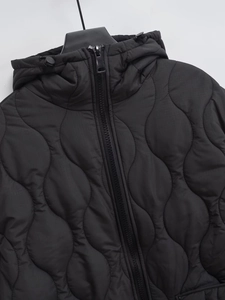Detail of black hooded jacket featuring wave quilted pattern and adjustable drawstring
