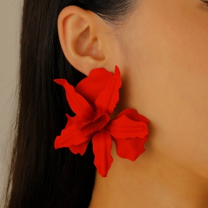 Close-up of a model wearing large matte red 3D floral earrings for party outfits