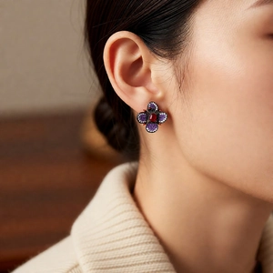 Détail de boucle d'oreille fleur vintage avec pierres rouges et violettes portée par mannequin