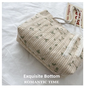 Flat bottom detail of beige straw tote bag with green leaf embroidery and lace trim