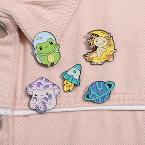 Close-up of cute frog astronaut, mushroom and rocket enamel pins on pink denim jacket