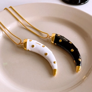 Detail of vintage horn pendants in black and white enamel with gold dotted patterns
