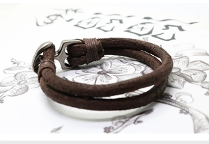 Macro shot of retro brown braided leather bracelet featuring vintage anchor hook clasp