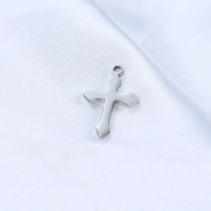 Detailed view of polished silver stainless steel cross pendant on white silk fabric