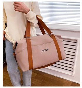 Pink canvas travel tote bag with brown straps and HAYUN logo carried by a model