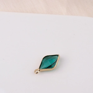 Macro shot of an emerald green rhombus crystal pendant in a gold setting for jewelry making