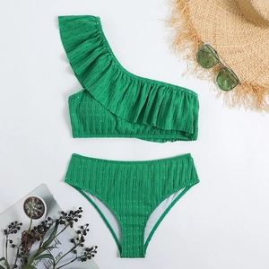 Flat lay of green one-shoulder ruffle bikini set with high waist bottom and vacation decor