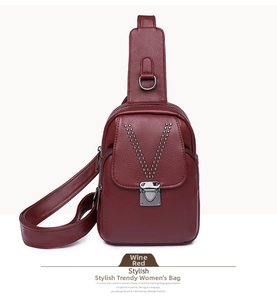 Détail du cuir grainé bordeaux avec des rivets argentés en forme de V sur le sac à main