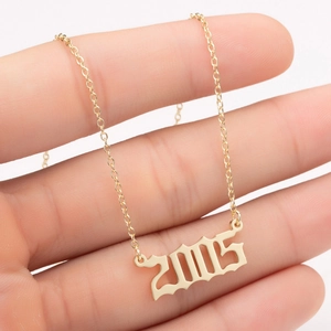 Detail of 2005 year number pendant in gold finish held by hand to show size
