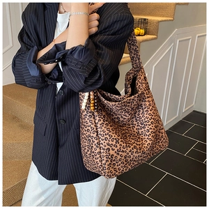 Detailed view of a stylish leopard print oversized tote bag worn with a striped blazer