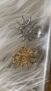 Close-up of gold and silver sun rings with textured hammered metal spiral design