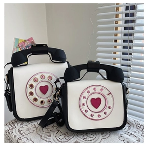 Detailed view of two vintage telephone-shaped crossbody bags with heart dial