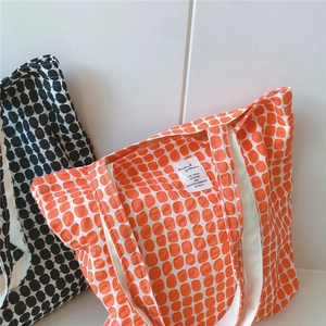Detailed view of canvas tote bag with polka dot print and animal pattern label