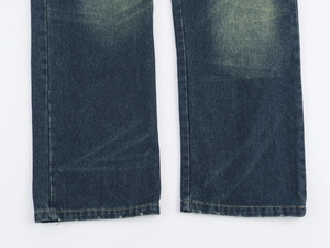 Détail du pantalon en jean bleu foncé montrant les coutures et l'effet délavé au bas