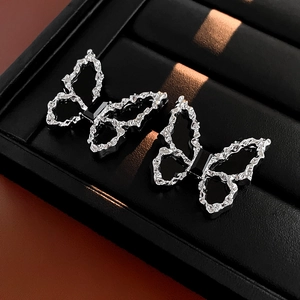 Close-up of silver butterfly earrings with hammered texture and black emerald cut stone