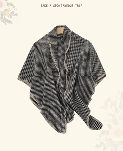 Detailed knit texture of a thick houndstooth plaid shawl hanging on a wooden hanger