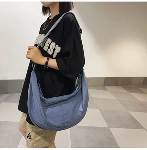Gros plan d'un sac messager en nylon bleu porté par un mannequin dans un style décontracté