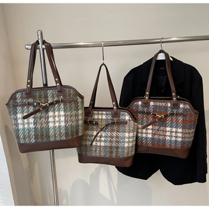Three plaid tote bags with leather trim hanging on a rack in a professional setting