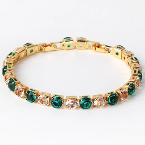 Detailed view of single row 6mm emerald and white zircon tennis bracelet in gold plating