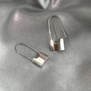 Minimalist silver industrial U-shaped lock earrings on grey silk fabric background