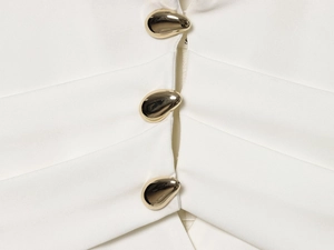 Close-up of elegant gold water-drop metal buttons on white textured blazer fabric