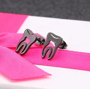 Detail of cute tooth shaped black stainless steel stud earrings on a white gift box