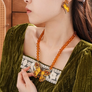 Macro detail of amber butterfly necklace with faceted beads and matching earrings