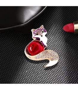 Macro view of vintage fox brooch with red enamel body and crystal tail detail
